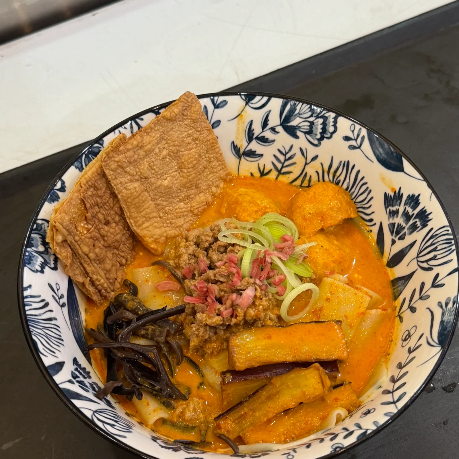 A bowl of curry ramen with fried bean curd skin and minced meat